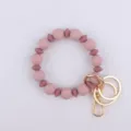 Llavero de pulsera de cuentas de silicona con herrajes metálicos dorados, detalle elegante. - Malva Oscuro