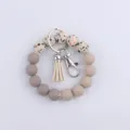 Porte-clés bracelet en perles de silicone avec pompon en cuir et anneau en métal pour clés. - Beige