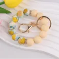 Silicone beaded wristlet keychain with floral print and gold metal hardware ring. - Off White