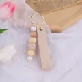 Elegante portachiavi in pelle beige fatto a mano con perle in silicone e legno per borse. - Beige