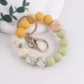 Silicone bead wristlet keychain with floral print, wooden accent, and gold clasp for women. - Turmeric