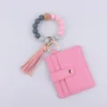 Detalle llavero cuentas silicona, tarjetero PU rosa, accesorio pulsera borla vista cercana. - Rosa rojo