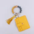 Detalle de primer plano del tarjetero de cuero PU amarillo, cuentas de silicona y borla. - Amarillo
