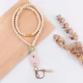 Detail shot of wooden bead lanyard featuring a cute pink apple pendant and metal tassel clasp. - Wool Ball Style