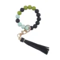 Silicone beaded bracelet keychain detail featuring black and green beads with leather tassel. - Black
