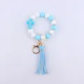 Close-up of blue white silicone bead cross keychain bracelet with leather tassel detail - Blue