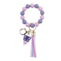 Detailed shot of silicone beaded wrist keychain with purple butterfly charm and rainbow tassel. - Purple