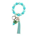 Close up view of turquoise silicone bead wristlet keychain with green butterfly charm and tassel. - Green