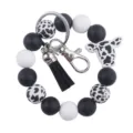 Llavero de pulsera con cuentas de silicona de vaca, borla de cuero PU negro y cierre metálico. - Vaca Blanco Negro