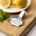 Detail view of 430 stainless steel manual lemon squeezer on a wooden board - 8.5x7x3.5cm Lemon Clip