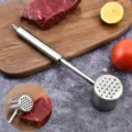 Close-up of professional stainless steel meat tenderizer hammer on a wooden cutting board - Default
