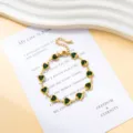 Detailansicht des vergoldeten Edelstahl Armbands mit grünen Herz Kristall Zirkon Elementen. - Armband / Grün