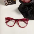 Primer plano detallado de la elegante montura de gafas estilo ojo de gato roja en mesa moderna. - Rojo