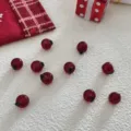 Detalle de cuentas de manzana de vidrio rojo, perfecto para colgantes de joyeria navidenos. - Cojín de manzana