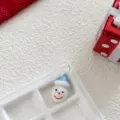Close-up detail of handmade glass snowman pendant charm with blue hat and clear hanging loop. - Blue Hat Snowman