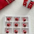 Close-up detail of Christmas glass beads with red hat and green bow design for DIY crafts. - 12mm Santa Hats