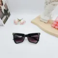 Detailansicht modischer schwarzer Cat-Eye-Sonnenbrille mit Metalldetails auf dem Tisch. - Schwarzer Rahmen Doppelt Graue Linse