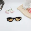 Detaillierte Nahaufnahme von modischen schwarzen Sonnenbrillen im Cat-Eye-Stil mit braunen Gläsern. - Schwarzer Rahmen Tee Gläser