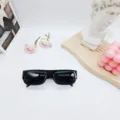 Primer plano de gafas de sol retro negras de montura estrecha con accesorios decorativos. - Montura Negra Lente Gris