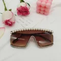 Détail de lunettes de soleil oversize sans monture, verres bruns avec perles et strass. - Imprimé léopard