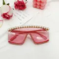 Vue détaillée de lunettes de soleil tendance surdimensionnées et sans monture avec perles et strass. - Rose
