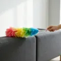 Vista detallada de un plumero colorido y flexible en un sofá gris para la limpieza del hogar. - Multicolor