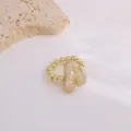 Primer plano detallado de anillo de cobre bañado en oro con letras de circonita micro-pavimentadas. - Letra A