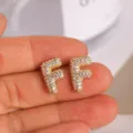 Close-up of the gold-plated letter F stud earrings with sparkling pave cubic zirconia details. - Letter F