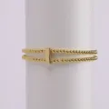 Double strand gold beaded stretch bracelet with smooth central metal connector piece. - Letter I