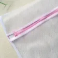 Gros plan sur le sac a linge en maille blanche avec fermeture eclair rose, filet delicat. - Maille large avec bordure