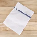 Sac de lavage à linge en filet blanc avec fermeture éclair bleue posé sur du bois. - 30x40cm / Filet Fin Gris 70g Fermeture Éclair