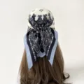Detail view of the elegant paisley print square scarf worn as a stylish hair accessory. - Beige Border Paisley