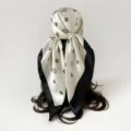 Detailed view of a black and white floral silk scarf styled as an elegant chic headscarf. - D9509 - Beige & Black