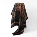 Close-up of black and orange paisley silk scarf with polka dot border, soft satin drape detail. - 88x88cm / Black
