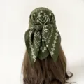 Close-up detail of dark green paisley square bandana scarf tied neatly on hair mannequin. - Concentric Circle Paisley