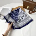 Detail view of a blue and white paisley patterned silk square scarf with elegant design. - Colorblock Half Paisley