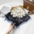 Detail shot of a stylish 68cm square scarf with classic paisley print and elegant blue border. - Beige Border Paisley
