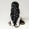 Detailed view of a black silk-like square scarf featuring elegant white floral prints. - D9509 - Black & White