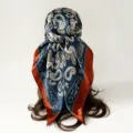 Detail view of a 90cm satin paisley square headscarf, elegant dark blue and rust brown shawl. - Blue