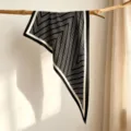 Detailed view of the elegant black and white striped triangle silk scarf draped on a wooden branch. - SJJ120 / Black