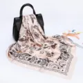 Detailed view of a stylish paisley print square silk scarf draped elegantly on a black handbag. - D9065-Beige