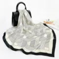 Detail view of the elegant black and white geometric silk scarf draped gracefully on a handbag. - D9158-White