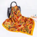 Detailed view of a vibrant yellow paisley print silk satin square scarf draped on a chic handbag. - D9045 Yellow