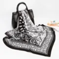 Detailed view of black and white paisley silk scarf draped on leather bag, elegant texture. - D9017-Black
