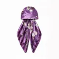 Detailaufnahme einer violetten Satin-Kopftuchmütze mit Blumenmuster und eleganter Textur. - Lila