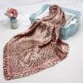 Leopard print satin square scarf detail showing smooth texture, stylish pink border and chic drape. - Pink