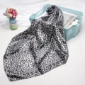 Detailed close-up of a chic black and white leopard print square satin silk scarf. - Black