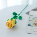 Handgemaakte gehaakte gele roos detail, close-up van wollen gebreide bloem met zachte textuur. - Geel