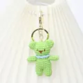 Close-up of the handmade green crochet bear pendant detail, showing fine knitting and metal ring. - Metal Buckle Bear / Green