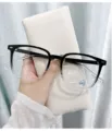 Nahaufnahme Detail der schwarz-transparenten Blaulichtfilter Brille in Hand, feiner Look. - Farbverlauf Schwarz / Blaulichtschutz (ohne Stärke)